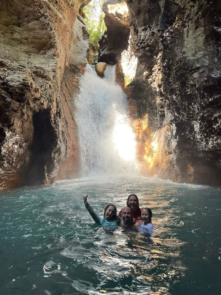 a group of people swimming in a body of water on a Waterfall Tour