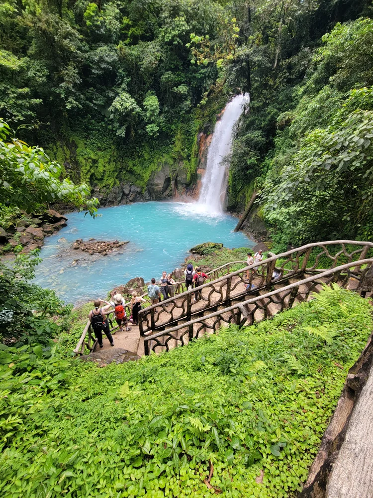 A tourist standing next to a Waterfall.